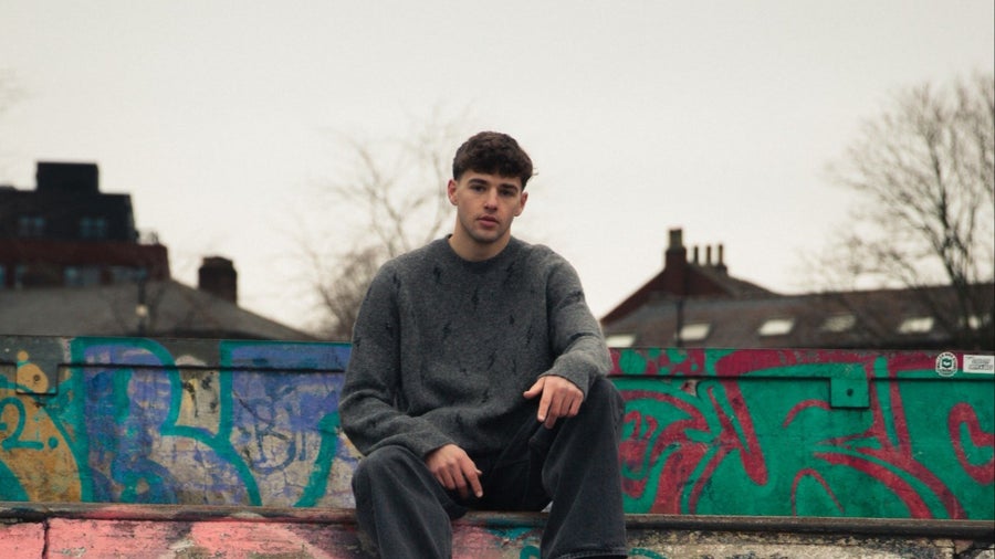 Will Edwards, Super Serious Coaching member, sitting on a graffiti-covered skate ramp